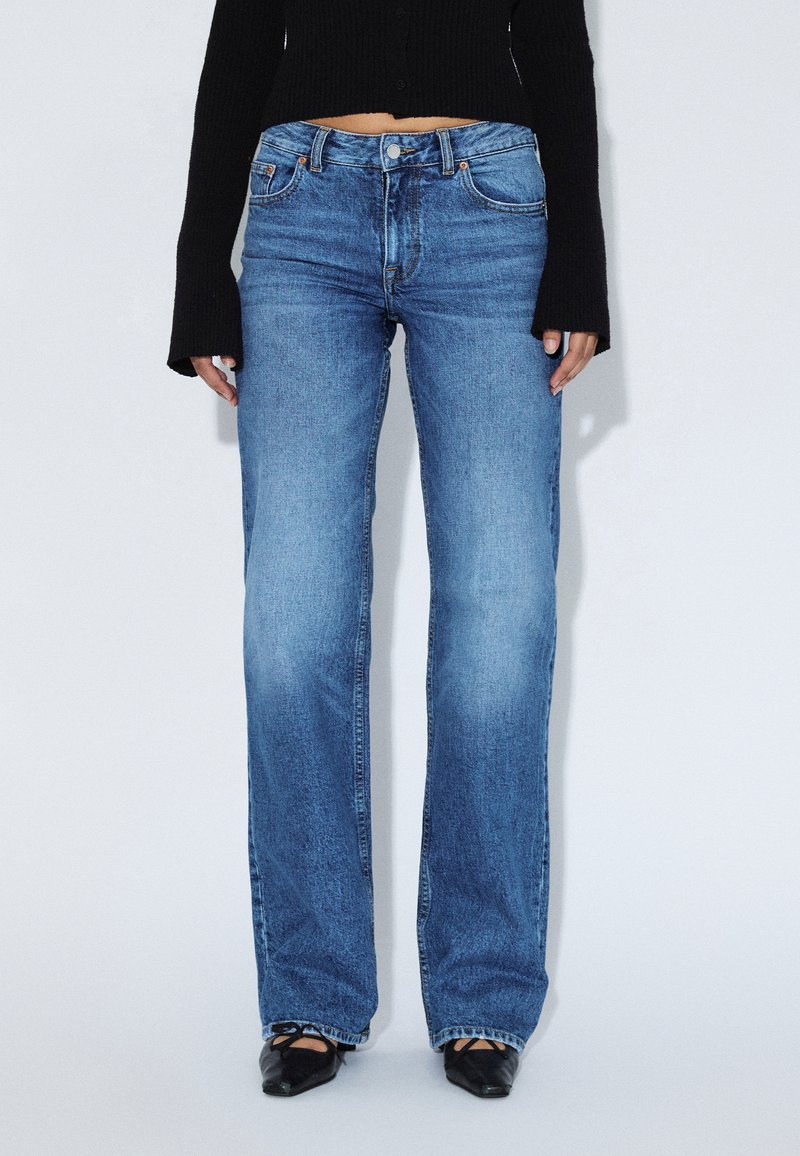 Jeans azzurri a gamba dritta con finitura slavata, cinque tasche e chiusura con bottone. Il tessuto ha una texture classica in denim.