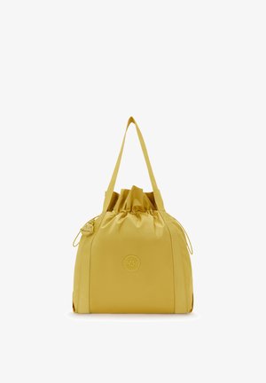 Bolsa tote amarilla con cordón, dos correas para el hombro, parche circular con logo en el frente y un pequeño llavero de mono adjunto.