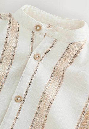 Lengvas medvilninis marškinys su balta baze, vertikaliomis smėlio spalvos ir juodomis juostelėmis, mandarino apykakle ir mediniais sagomis užtrauktuko juostoje.