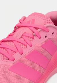 Φωτεινό ροζ αθλητικό παπούτσι με πλέγμα ύφασμα, μαξιλαρωμένη γλώσσα και γιακά, τρεις έντονες πλευρικές ρίγες και κορδόνια που δένονται σε φιόγκο.