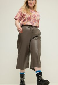 Hnědé kalhoty culotte z umělé kůže s elastickým pasem. Spárovány s růžovým topem s paisley vzorem a černými vojenskými botami.