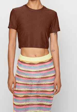 T-shirt court marron avec un logo Nike subtil, associé à une jupe tricotée à rayures multicolores avec des teintes pastel et une taille côtelée.