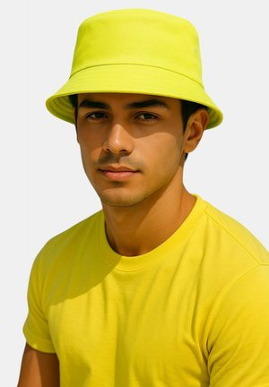 Cappello a secchiello giallo brillante con una larga tesa, realizzato in tessuto liscio, indossato con una camicia a maniche corte gialla coordinata.