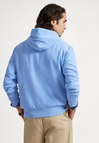 Ανοιχτό μπλε φούτερ με κουκούλα από απαλό βαμβάκι, με τσέπη καγκουρό και χαλαρή εφαρμογή. Ο σχεδιασμός περιλαμβάνει κουκούλα με κορδόνι και ριμπ μανσέτες.