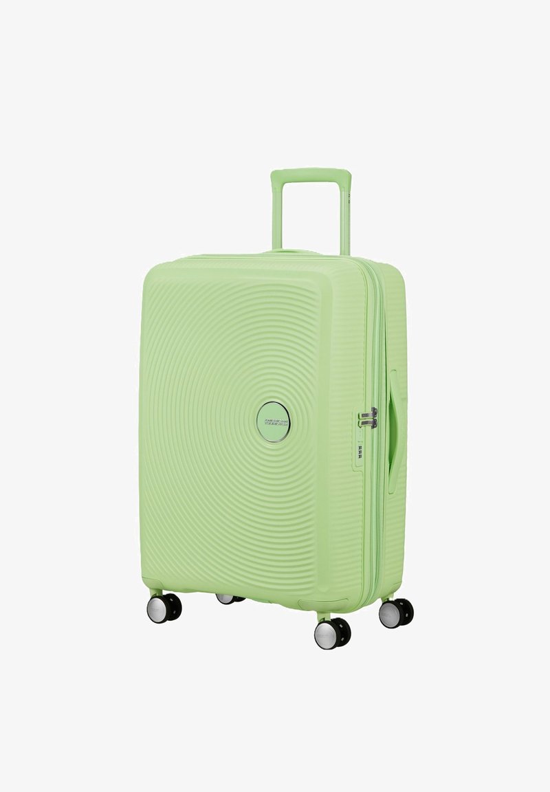 Valise rigide vert clair avec des cercles concentriques texturés, quatre roues pivotantes, poignée télescopique, poignée latérale et serrure à combinaison.