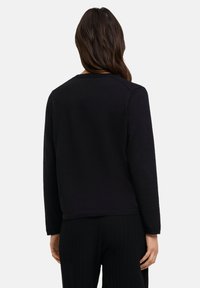 Schwarzer, langärmeliger Pullover mit Rundhalsausschnitt, geripptem Textur und entspannter Passform, der die Rückansicht zeigt und ein glattes Stofffinish aufweist.