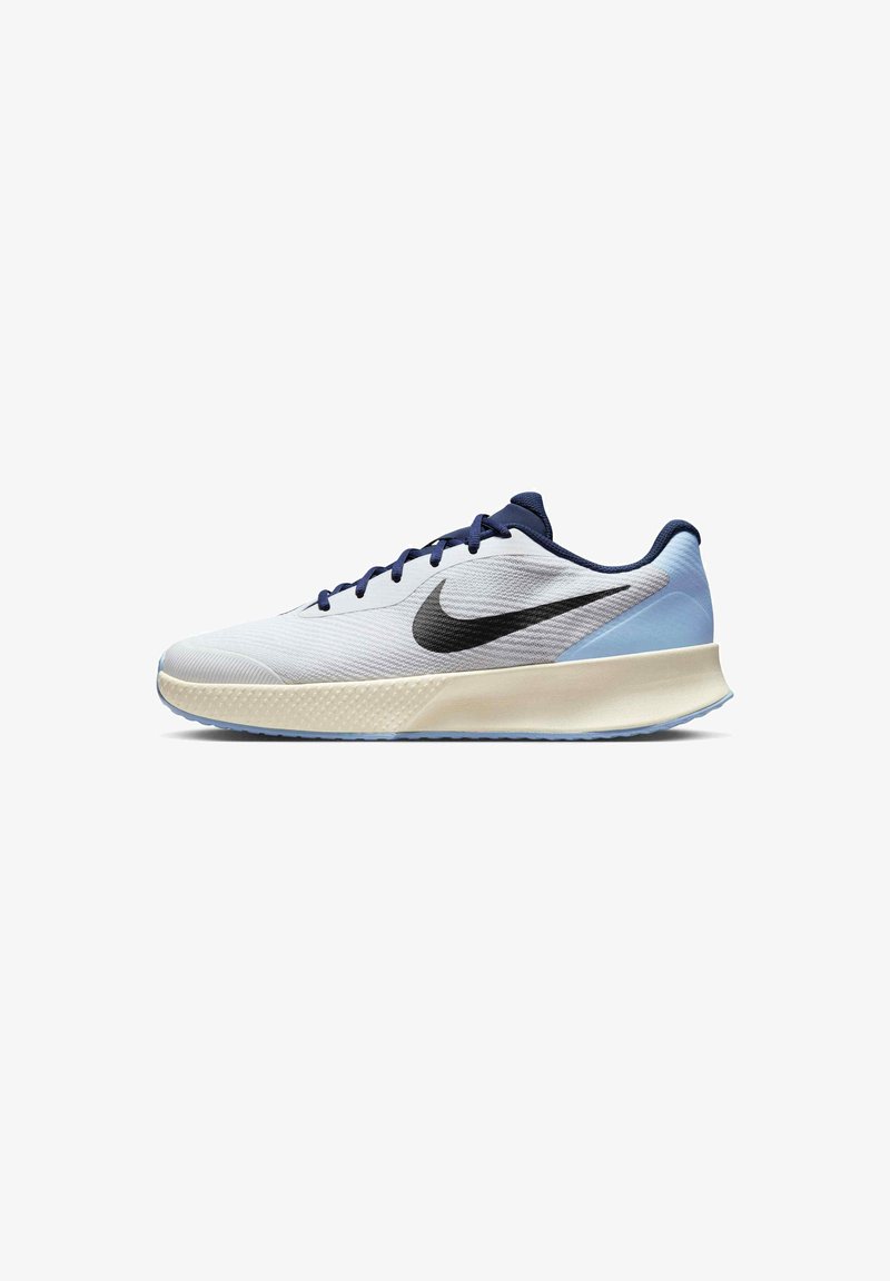 Nike trkaće tenisice s bijelim teksturiranim gornjim dijelom, tamnoplavim akcentima i crnim swoosh logom. Lagani dizajn s podstavljenim izrezom i mekanom petom.