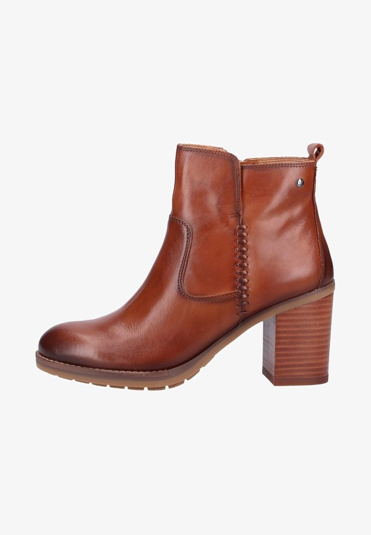Botte cheville en cuir marron avec talon bloc, coutures décoratives, languette de tirage et semelle en caoutchouc vue de côté.