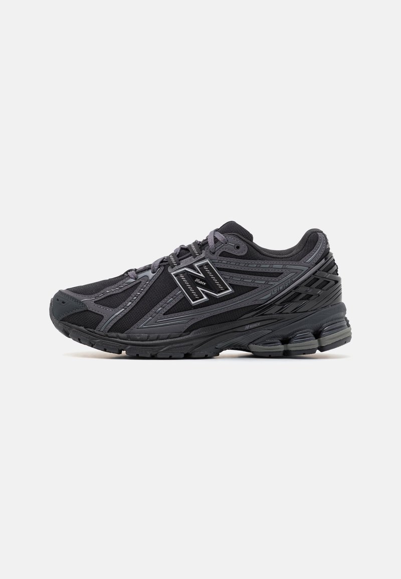 Baskets noires et grises avec une tige en mesh et synthétique, semelle amortissante et logo "N" visible sur le côté.