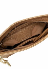Interno di una borsa a tracolla in pelle tan con motivo testurizzato, numerosi scomparti, chiusura a zip e fodera in tessuto chiaro. Logo del marchio visibile.