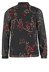 Blusa nera trasparente a maniche lunghe con colletto alto, caratterizzata da un motivo floreale in tonalità rosse, beige e verdi su uno sfondo scuro.