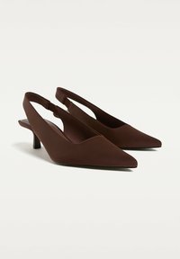 Chaussures slingback marron à bout pointu avec un petit talon et un design découpé au talon. Fabriquées en matériau lisse avec une finition mate.