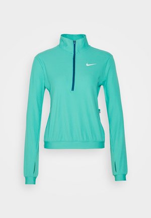 Pull de sport à manches longues couleur sarcelle avec une fermeture éclair partielle, des trous pour les pouces aux poignets et un petit logo blanc Nike sur la poitrine.