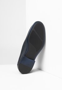 Suola delle scarpe blu navy in gomma, caratterizzata da un fondo nero testurizzato e un accentuato tallone blu navy liscio. Strutturata, con un design minimalista.
