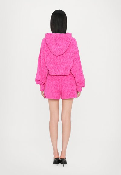 Roza kapuca iz frotirja z ustreznimi kratkimi hlačami, ki ima celoviti vzorec z logotipom Versace, sproščen kroj in elastičen pas.