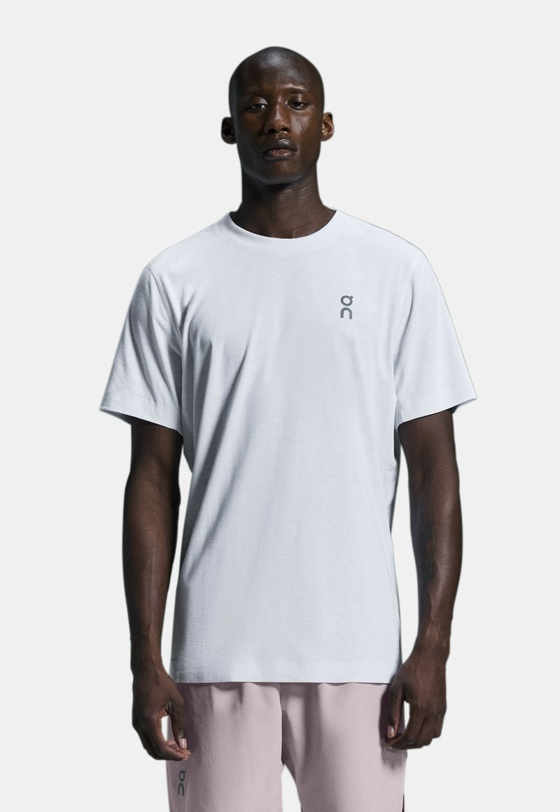 Weißes T-Shirt mit kurzen Ärmeln aus weichem Stoff. Hat ein kleines graues Logo auf der linken Brust. Klassisches Rundhalsdesign.