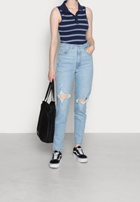 Polo tričko s námořnickým pruhováním, světle modré zvýšené ripped džíny, černá tote taška a černé tenisky s bílou podrážkou. Neformální outfit.