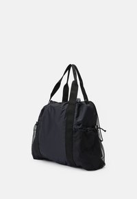 Svart nylon duffelbag med polstrede håndtak, med nettinglommer på siden og snøring. Glatt tekstur og romslig design.
