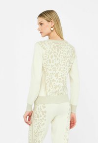 Maglione crema con un design a stampa leopardata di colore sabbia sul retro. Presenta polsini e vita a coste, ed è realizzato in un materiale a maglia morbido.