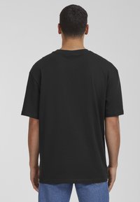 Black cotton t-shirt with a relaxed fit, short sleeves, and a crew neckline. Features a plain design with no visible logos or patterns.