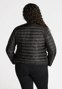 Chaqueta acolchada negra con costuras horizontales, con un cuello redondo y mangas largas, diseñada para ofrecer calidez y comodidad.