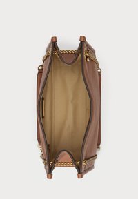 Καφέ δερμάτινη τσάντα με υφή, διακοσμημένη με χρυσές αλυσίδες, ανοιχτή κορυφή και εσωτερική επένδυση σε μπεζ απόχρωση που διαθέτει μια πλαϊνή τσέπη.