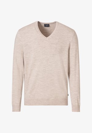 Beiger V-Ausschnitt Pullover, hellgraue Hose und braune Wildlederschuhe mit Espadrillesohlen. Model sitzt auf einem geflochtenen Holzstuhl.