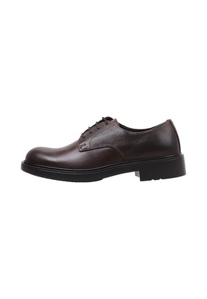 Zapato de piel marrón oscuro con cordones y punta redondeada, costuras en contraste y suela de goma negra gruesa. Diseño limpio y minimalista.