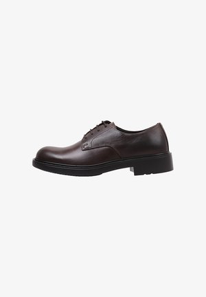 Dark brown leather lace-up shoe with a rounded toe, contrasting stitching, and a thick black rubber sole. Clean, minimalist design.