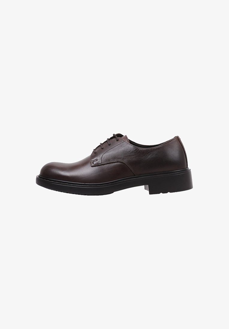 Chaussure en cuir marron foncé à lacets avec un bout arrondi, des coutures contrastantes et une épaisse semelle en caoutchouc noir. Design épuré et minimaliste.