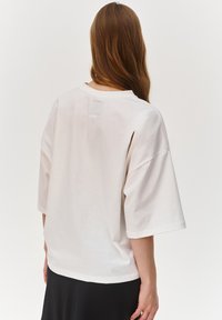 Oversized t-shirt w kolorze jasnobeżowym, wykonany z bawełny, z okrągłym dekoltem, krótkimi rękawami i prostym wykończeniem. Minimalistyczny design bez grafik.