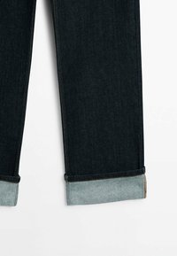 Mörkblå denimjeans med rak bendesign, med en uppvikt fåll i ljusblå denim. Stadig sömnad och ingen synlig hårdvara.