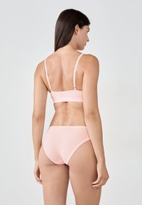 Ensemble de bikini rose comprenant un haut bralette ajusté avec des bretelles réglables et un bas taille haute, fabriqué à partir d'un tissu lisse avec des coutures minimales.