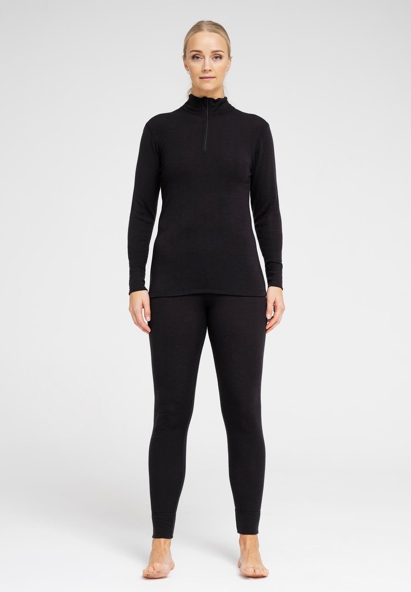 Sort termisk top med høj hals og lynlås, parret med matchende sorte leggings. Begge er lavet af et blødt og strækbart materiale for komfort.