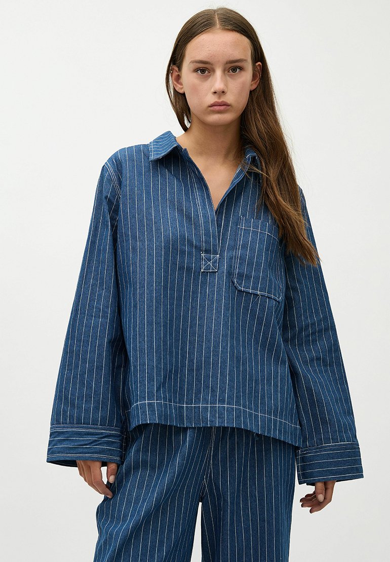 Blauw gestreepte denim shirt met een puntkraag, lange mouwen en een voorzak. De stof heeft verticale witte strepen en een relaxte pasvorm.