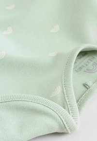 Mintgrön babydräkt med små vita regnbågsmönster, mjukt tyg, rundad halsringning och sydda detaljer vid fållen.