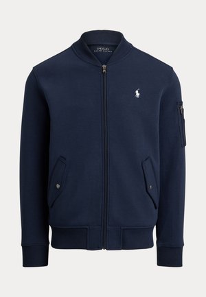 Navy blue zip-up bomber jacket in soft material, featuring a ribbed collar, two side pockets with snap buttons, and a small logo accent on the chest.