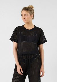 Zwarte korte mouwen top gemaakt van een gestructureerde, geperforeerde stof. Het heeft een ronde halslijn en een cropped ontwerp voor een moderne uitstraling.