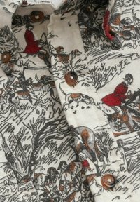 Tessuto della camicia con stampa di scena di caccia che presenta cavalieri in giacche rosse, diversi cani da caccia, alberi e bottoni marroni su sfondo crema.