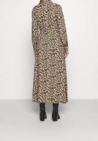 Takakats välimus naisega, kes kannab pikka, lillelist kleiti pikkade varrukatega ning musti kontsaga ankle-botte.