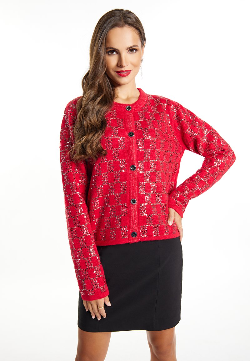 Cardigan roșu din material tricotat, cu modele din paiete într-un design cu carouri și butoane negre, asortat cu o fustă neagră.