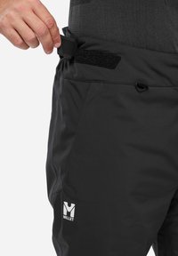 Schwarze Outdoor-Hosen mit verstellbarem Taillengurt, aus strapazierfähigem Material, mit einem Millet-Logo an der unteren Seite.