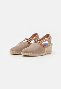 Alpargatas de cuña de ante en color beige con diseño de tiras entrecruzadas y suela tejida de yute. La punta redondeada y la textura suave complementan la ropa casual.