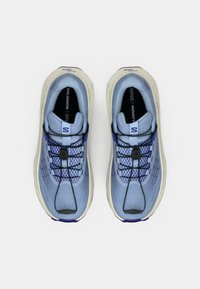 Ανοιχτό μπλε παπούτσια για τρέξιμο με υφή στην επάνω επιφάνεια, μαύρα κορδόνια και μεσαία σόλα σε κρεμ χρώμα. Διαθέτει κομψό σχεδιασμό και λογότυπο στη γλώσσα.