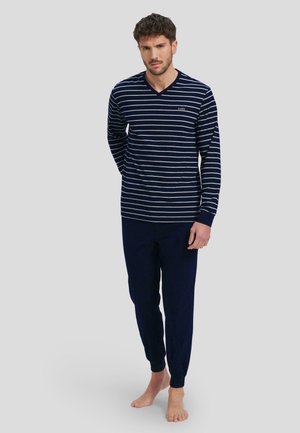Blusa de manga larga en rayas navy y blanca con escote en V, combinada con pantalones navy de cintura elástica, ambos de una tela suave. Branding minimalista en el pecho.