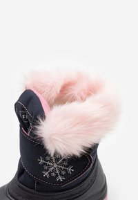 Insulated winter boot with a navy fabric upper, pink faux fur lining, and a snowflake pattern near the ankle. Black rubber sole.