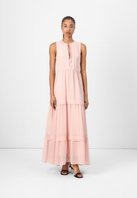Abito maxi in morbido tessuto rosa, con scollatura tonda, dettaglio a fiocco sul davanti e gonna a strati con accenti a righe orizzontali.