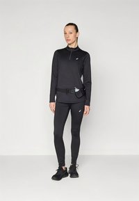 Black athletic long-sleeve top with a zippered collar, paired with matching leggings. Includes a belt with a water bottle holder. Black shoes.