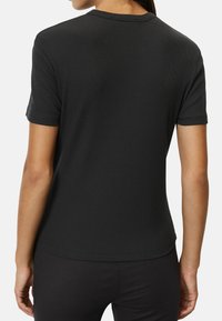 Black ribbed t-shirt with a round neckline, short sleeves, and a fitted silhouette, showcasing a smooth texture and subtle tailoring.
