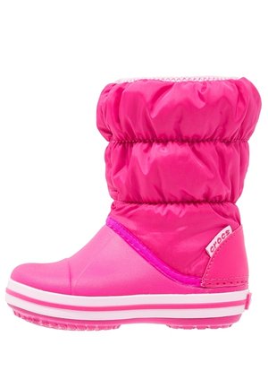 Botte d'hiver isolée rose vif avec dessus matelassé, semelle en caoutchouc et étiquette à logo Crocs sur le talon.